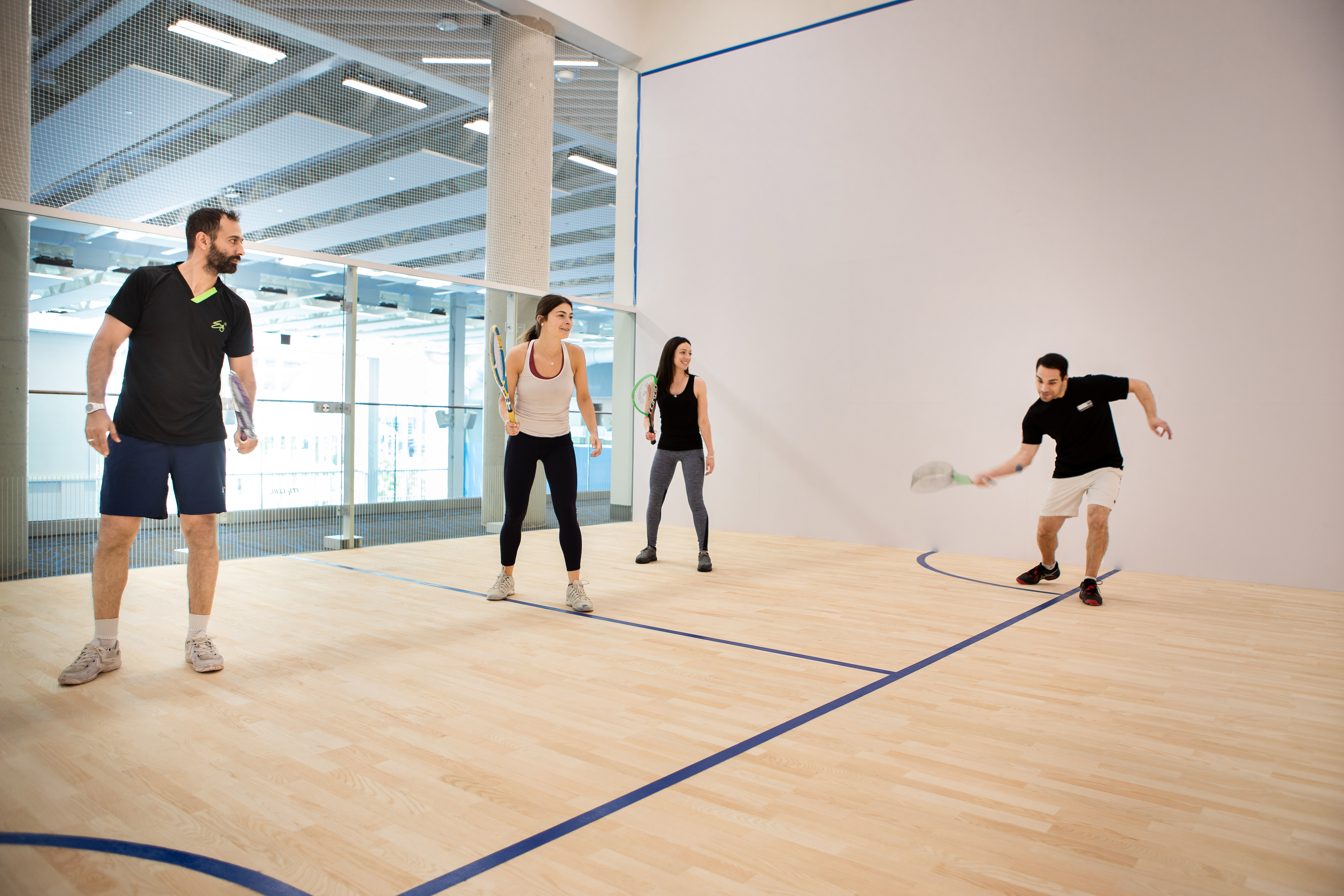 4 people playing squash on a court